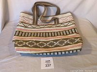 Front view of the large Stephanie Nicole tote bag showing its pink and beige beaded and studded woven exterior with shoulder straps.