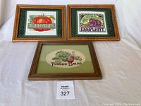 Photo showing all three framed embroidered kitchen pictures arranged on a white cloth background.