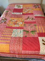 Twin quilt laid flat showing colorful patchwork squares and whimsical monkey appliques in shades of pink, orange, yellow, and green.
