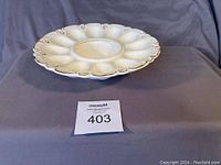 Full view of a vintage ceramic egg plate with hand-painted gold trim, showing the scalloped edges and twelve egg holders around a central well.