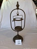 Full view of the vintage heavy metal candle holder on a white backdrop showing the entire piece from base to top finial.