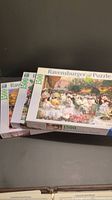 Three Ravensburger 1500 piece puzzle boxes stacked, showing puzzle artwork and logo.
