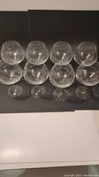 8 clear crystal red wine glasses arranged in two rows on a black and white surface, showing front and top view of round bowls and stems.