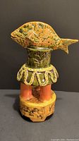 Right side view of the fish trophy sculpture showing orange and green glaze details on the fish and base with coral columns.