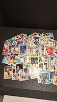 Pile of over 300 vintage hockey cards spread on black surface, showing colorful player photos and team logos.