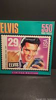 Front of the sealed puzzle box showing colorful Elvis Presley postage stamp artwork and 550 piece count.