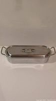 Rectangular stainless steel fish poacher/steamer with lid and handles, viewed from front side.