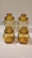 Four vintage amber bubble glass canisters with lids, two large and two small, arranged on a surface.