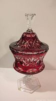 Front angle view of the ruby red cut crystal candy dish with lid and clear pedestal base.