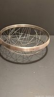 Front angle photo showing the full silver wire basket bowl with open wire design and smooth metal rim.