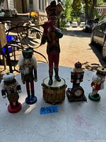 Photo showing four nutcracker figurines and one flute player figurine on a table outdoors