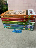 Stack of 5 Pokémon Adventures manga books showing colorful spines and volume numbers 1 to 5 by Hidenori Kusaka and Mato.