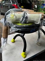 Photo showing the Ab Doer 360 main frame with curved black legs and yellow rubber foot caps, plastic wrapped seat, and foam wrapped assembly parts.