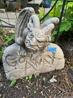 Front view of the concrete gargoyle statue with visible intricate facial features and 'Go Away' inscription on the base.