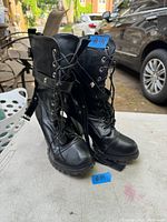Front view of the pair of black leather boots showing lace-up design, thick soles, and high heels