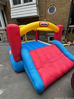 View of the front of the inflated bounce house showing the slide and the Little Tikes logo on the yellow arch overhead.
