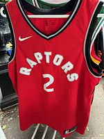 Front view of red Toronto Raptors basketball jersey with white 'RAPTORS' and number 2, Nike swoosh logo on chest