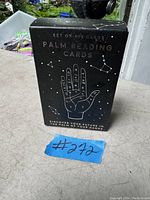 Photo of the black box with 100 palm reading cards, showing the front cover with palm illustration and stars.