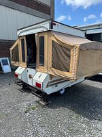 Rear and side view of camper with pop-up roof raised and canvas sides deployed