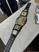 Full view of the WWE wrestling championship belt laid out on a surface showing metal plates and snap holes.