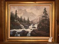 The full view of the framed oil painting showing mountainous landscape with waterfall and pine trees.