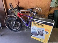 Three bicycles packed together in garage with Rhode Gear Ultra Shuttle 3 bicycle carrier box in front.