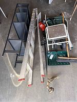 Photo showing ladder, shelving unit, folding wheelbarrow, garden rake, shovel, and weed eater.
