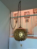 Full view of hanging swag light showing spherical scalloped plate design, chain and cord