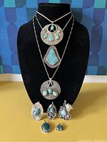 Front-on view of eight sterling pendants displayed on bust and table