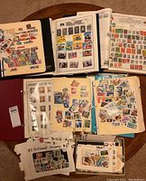 Overview of several open stamp albums and loose stamps scattered on a table.