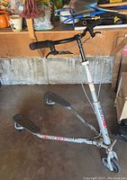 Side view of the Trike T67s scooter showing silver frame, wheels, and handlebars.