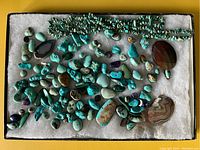 Overhead view of entire lot showing chip bead strands at top, scattered turquoise nuggets, beads and polished slices on white background