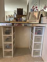 Wide view of the vanity area with plastic drawer storage units and vanity mirrors above, showing organization of hair supplies and perfumes.