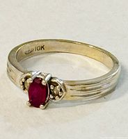 Front view of ring showing oval red center stone and round accent stones