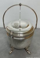 Front view of silver over copper ice bucket with lid closed and arch handle upright.