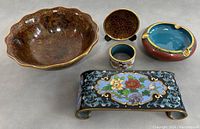Five Chinese cloisonné decorative pieces clustered on flat surface showing variety and colors.