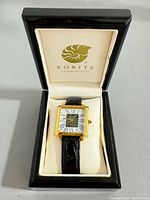 Korite International wristwatch displayed in original black lacquered presentation case with cream interior and Korite logo.