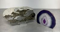 Soap stone etching of wolf scene on clear stand alongside purple agate quartz crystal candle holder