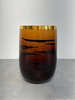 Full front view of the vase showcasing amber to dark brown gradient with black horizontal streaks and gold rim.