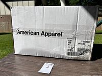 Box of American Apparel shirts showing brand and quantity (72 pieces) and size medium.