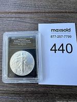 Front side of American Eagle Silver Dollar coin in plastic protective case, showing Walking Liberty design and authentication label.