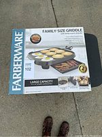 Box showing Farberware Family-Size Griddle with product information including large 16 x 14 inch cooking surface and features like adjustable temperature control and keep warm drawer.