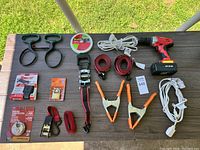 Overview of lot showing cordless drill, clamps, ratchet straps, cords, tape, and small hand tools
