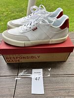Side view of Levi's white sneakers with red heel accent and box showing "Responsibly Made"