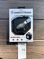 Front box of NFL wireless Bluetooth speaker with Philadelphia Eagles logo, Shockbox LED branding, and features listed including shock proof, water resistant, and LED lights that sync to music.