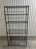 Front view of black metal wire shelving unit showing four adjustable wire shelves and rectangular frame.