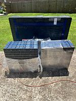 Stack of modular interlocking floor tiles shrink-wrapped for protection, next to a hard plastic storage case with handle.