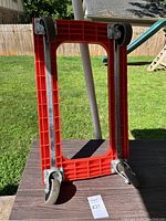 Underside view of the moving dolly showing the four swivel caster wheels attached to the frame.