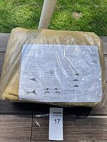 Sun shade sail folded in plastic packaging, showing label with installation instructions.