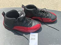 Side view of the pair of black and red Nike Air Jordan 12 Retro sneakers showing leather uppers and laces.